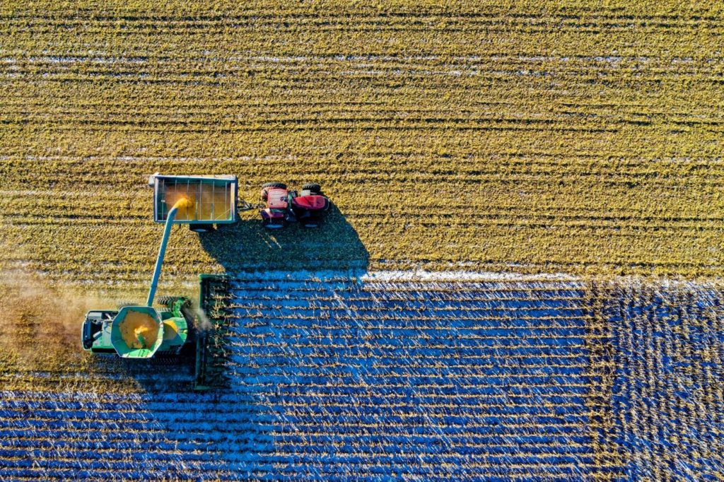 Top view of Combine Harvester’s Grain Tank, together with unloader and alongside tractor.